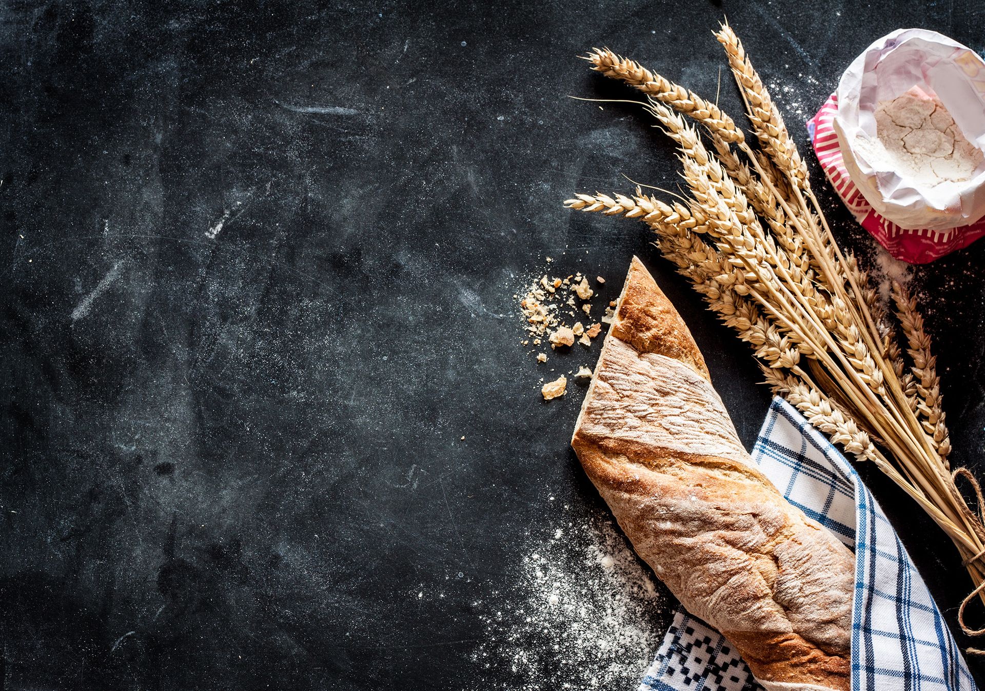 Baguette und Weizen liegen auf einem dunklen Hintergrund